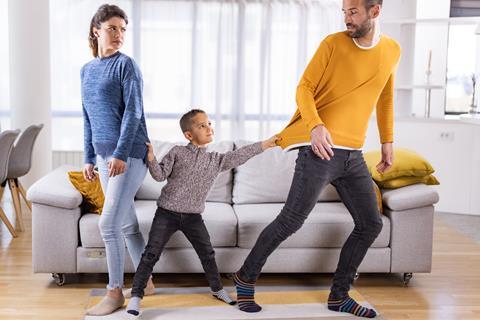 A young boy grabs hold of his mum and dad to pull them close to eachother